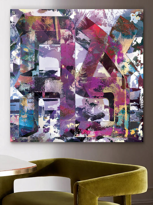 Abstract wall art featuring large stylized AHAVA letters in purple, pink, teal, black, and white, displayed above a green chair and white table in a modern interior setting.