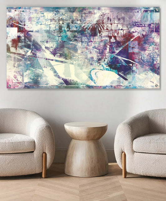 A large abstract Western Wall metal wall art print with a collage-like texture in shades of blue, purple, white, and pink, displayed above a modern white sofa in a bright, contemporary living room.